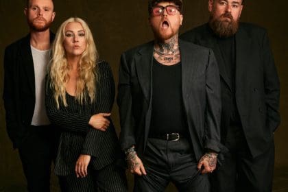 The four members of band Lottery Winners (3 men and one woman) dressed in black against a black background